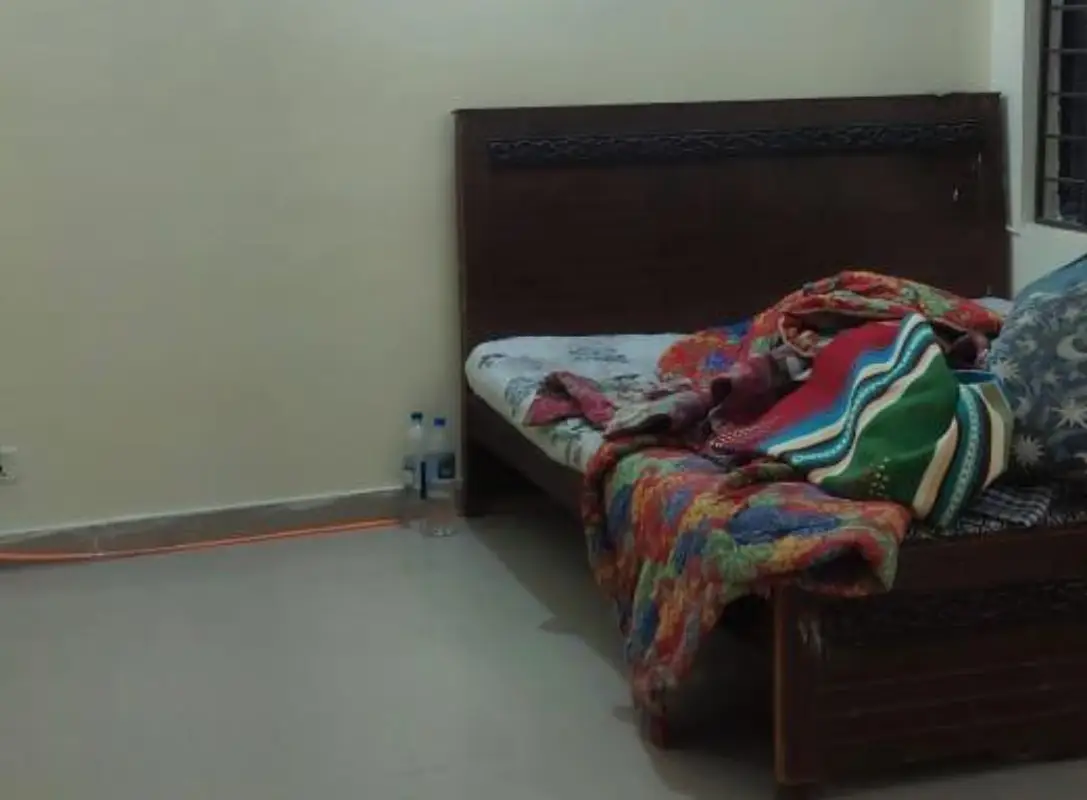 House for sale Umar Block – simple bedroom with wooden bed, colourful quilt and tiled floor