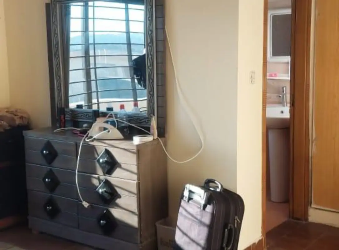 House for sale Umar Block – bright bedroom corner with dresser, mirror, suitcase and attached bath